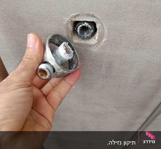 יד מחזיקה חלק ברז מנותק מהקיר